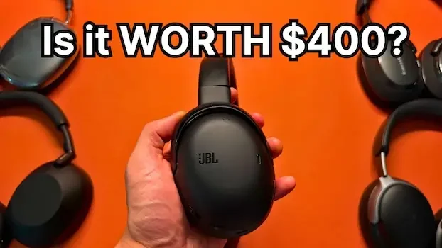 Holding JBL Tour One M3 headphones with Apple AirPods Max, Sony WH-1000XM6, Bose QuietComfort Ultra, and Bowers and Wilkins Px7 S3 in background
