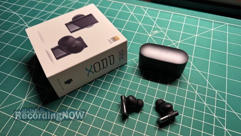 Status Pro X wireless earbuds in Black Alloy next to charging case and original box packaging