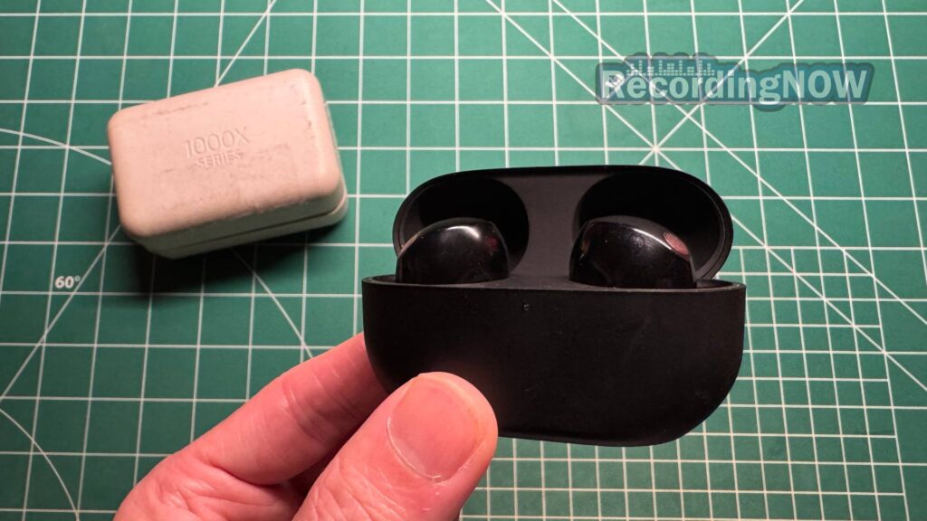 blog-img-1693067280109 Holding Sony WF 1000XM5 wireless earbuds in Black inside charging case with original box packaging in background