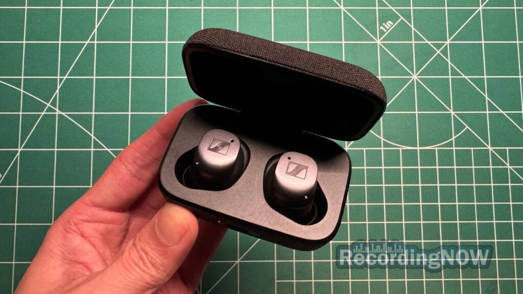 Holding Sennheiser Momentum True Wireless 4 earbuds in charging case