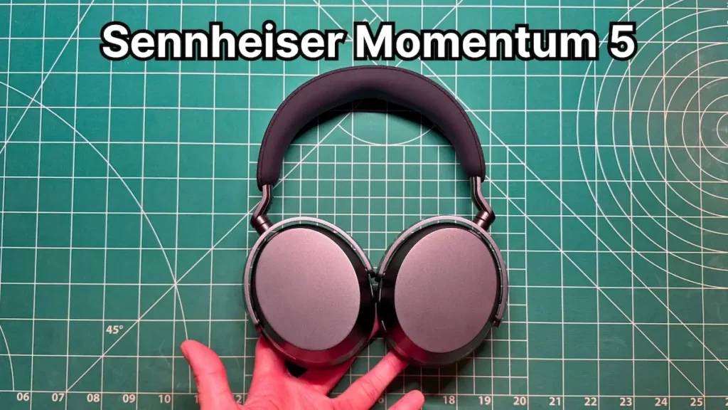 Holding Sennheiser Momentum 5 headphones in hand