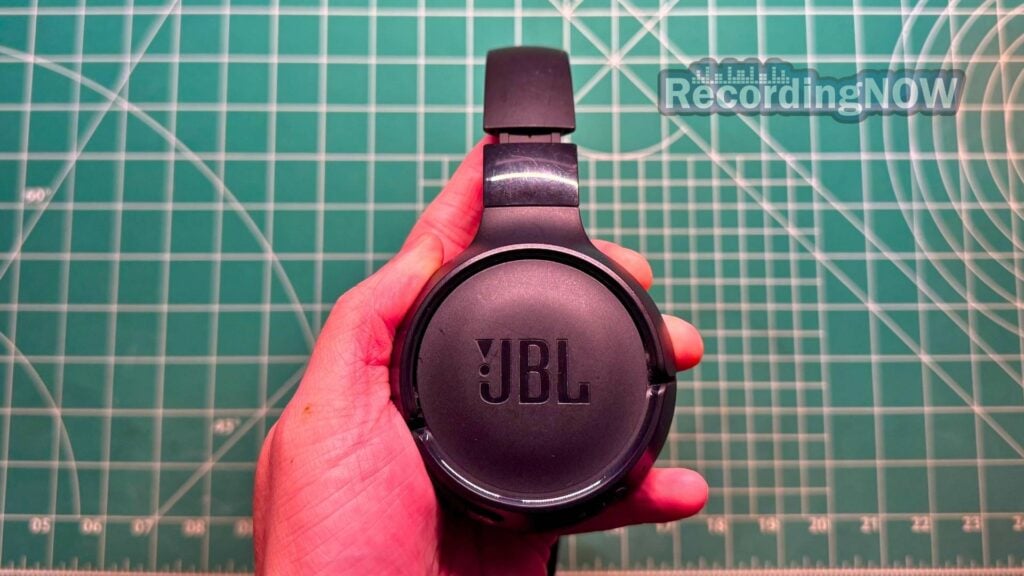 Holding JBL Tune 520BT headphones in black in hand