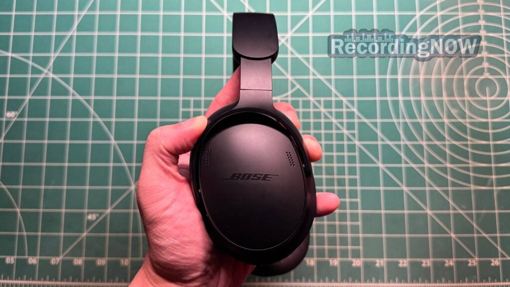 Holding earcup of Bose QuietComfort 2nd Gen headphones in hand