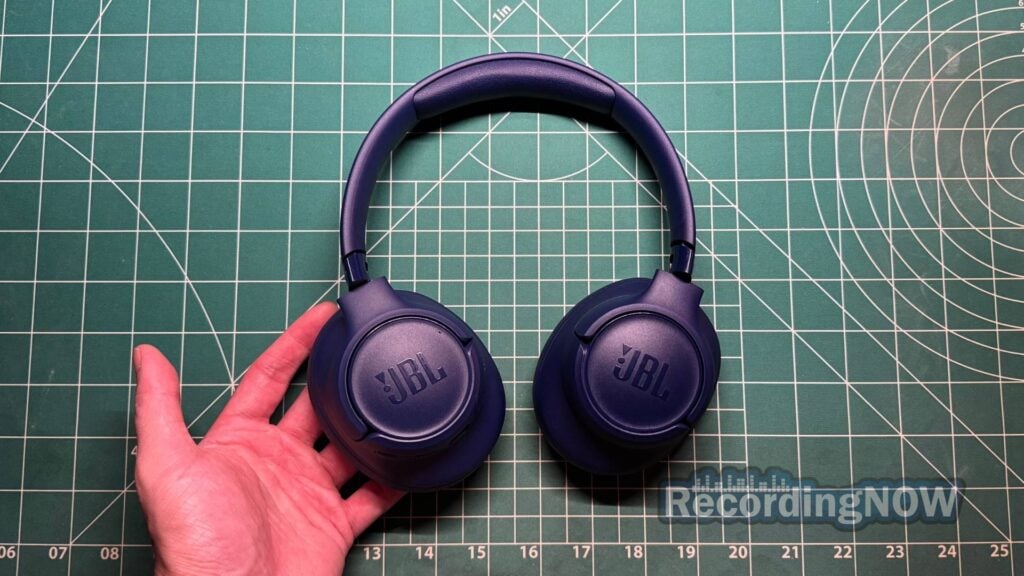 Holding JBL Tune 730BT wireless headphones in blue color