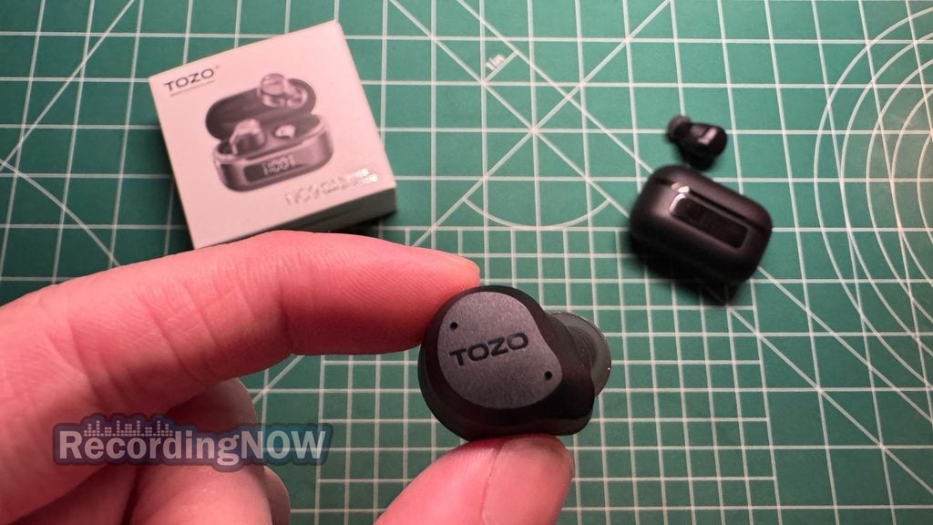 Holding TOZO NC9 wireless noise cancelling earbuds in hand